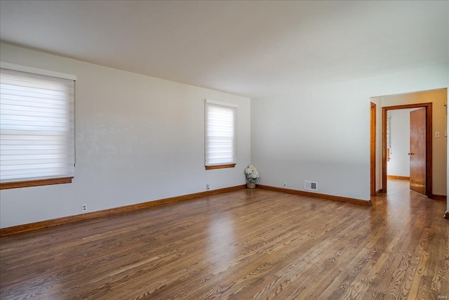 empty room featuring visible vents, baseboards, and wood finished floors