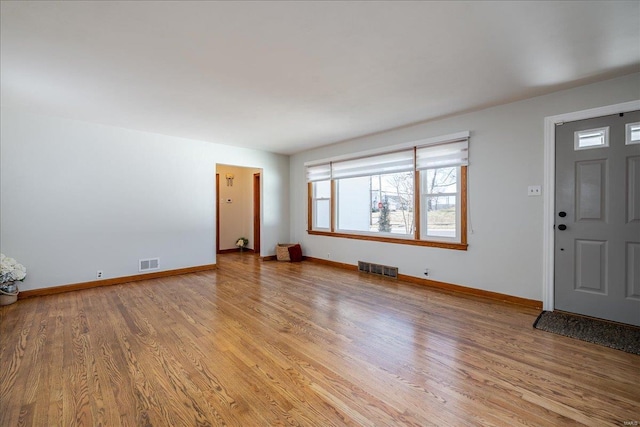 interior space featuring light wood-type flooring, visible vents, and baseboards