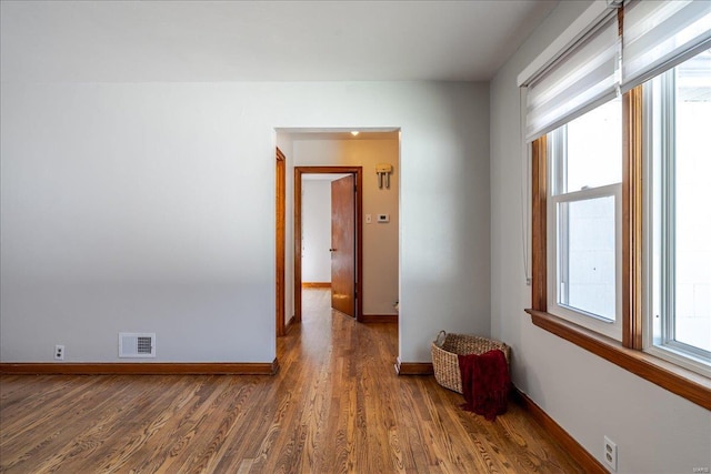 spare room with baseboards, visible vents, a wealth of natural light, and wood finished floors