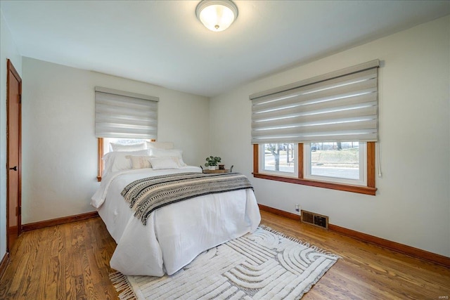 bedroom featuring visible vents, baseboards, and wood finished floors