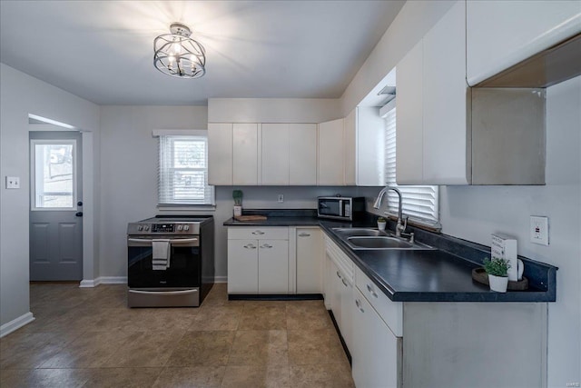 kitchen with stainless steel appliances, dark countertops, white cabinetry, and a sink