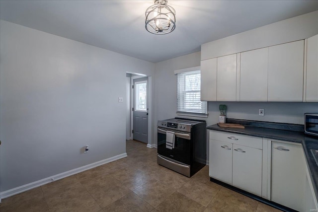 kitchen with dark countertops, stainless steel electric range, white cabinetry, and baseboards