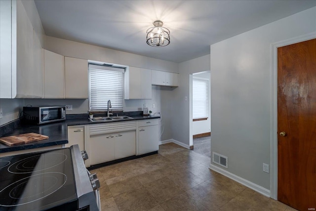 kitchen featuring visible vents, white cabinets, dark countertops, appliances with stainless steel finishes, and a sink