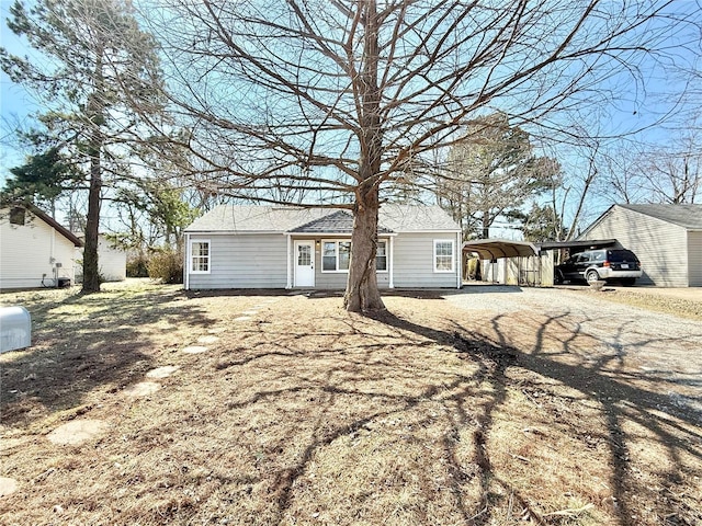 ranch-style house featuring dirt driveway and a carport