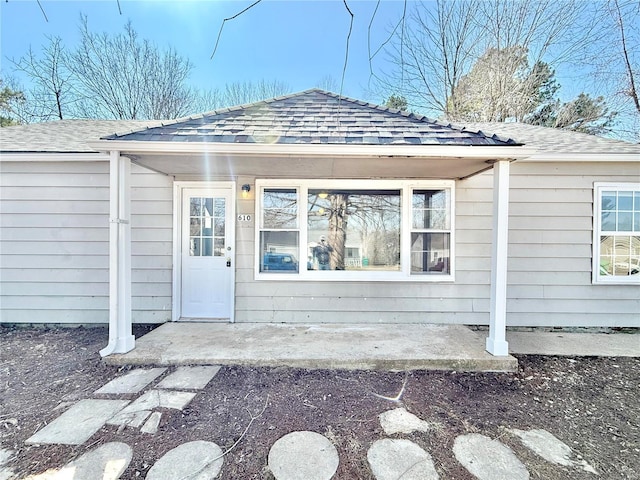 doorway to property with roof with shingles