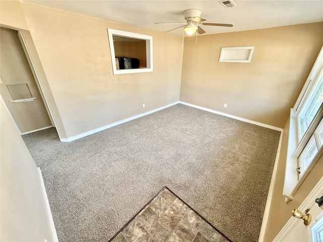 carpeted empty room featuring a ceiling fan, visible vents, and baseboards