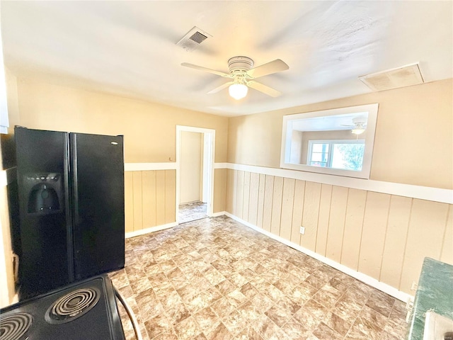 kitchen featuring black refrigerator with ice dispenser, wainscoting, visible vents, and a ceiling fan