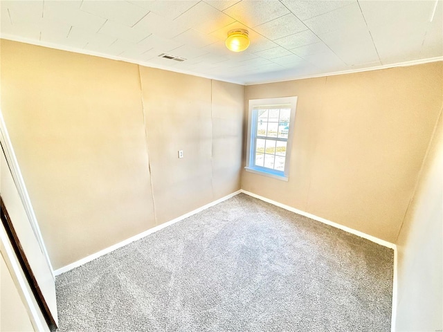 carpeted spare room with baseboards, visible vents, and crown molding