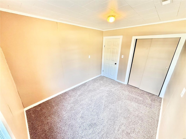 unfurnished bedroom with carpet floors, a closet, baseboards, and crown molding