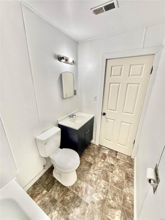 bathroom featuring toilet, stone finish flooring, vanity, and visible vents