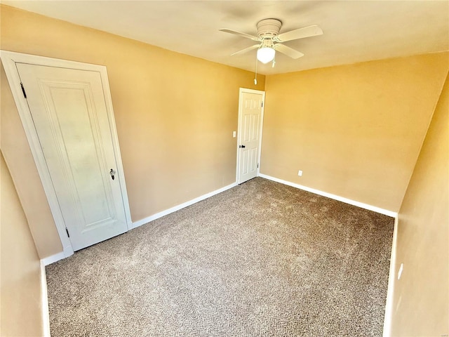 carpeted empty room with a ceiling fan and baseboards