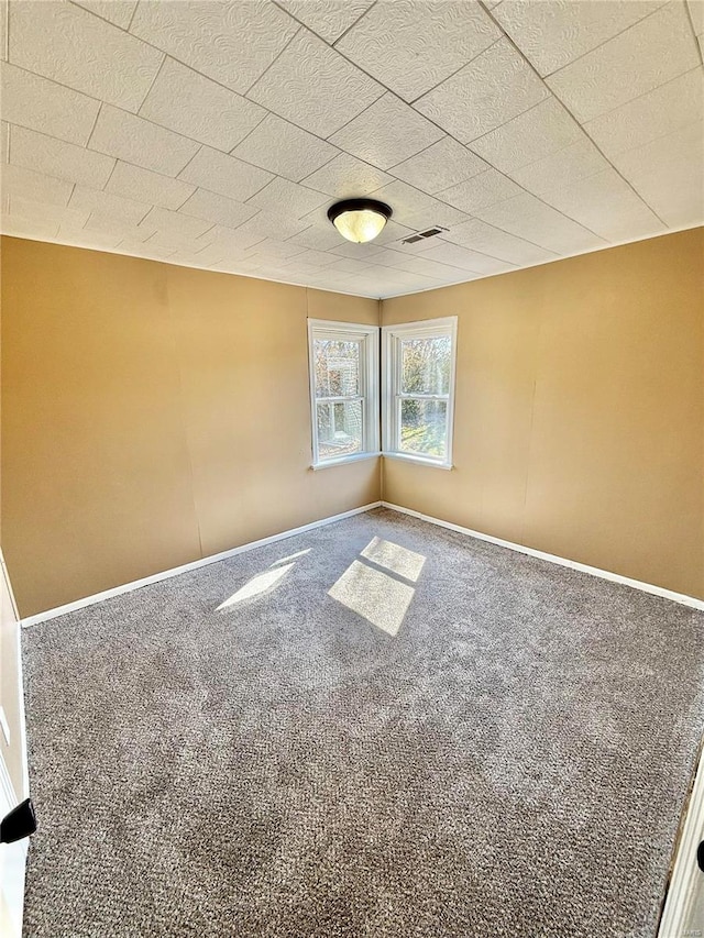 carpeted spare room with visible vents and baseboards