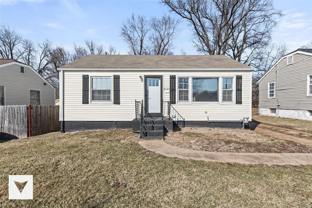 view of front facade with entry steps, fence, and a front yard