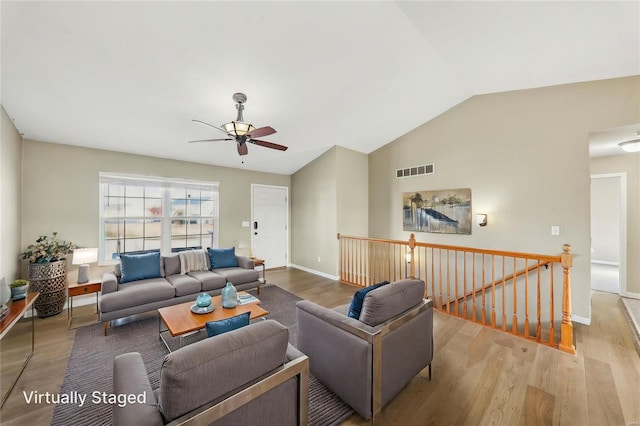 living area featuring vaulted ceiling, wood finished floors, visible vents, and baseboards