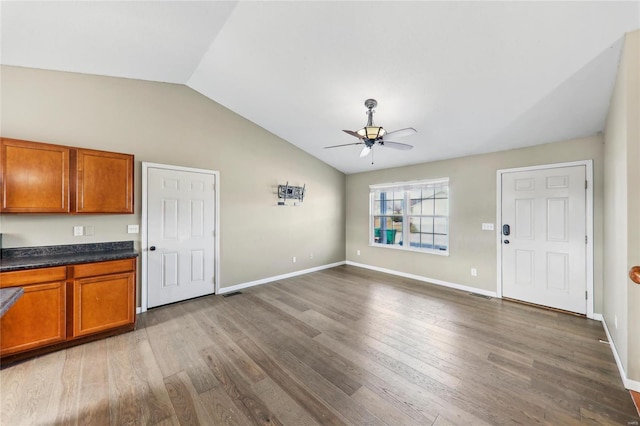 kitchen with vaulted ceiling, brown cabinets, and wood finished floors