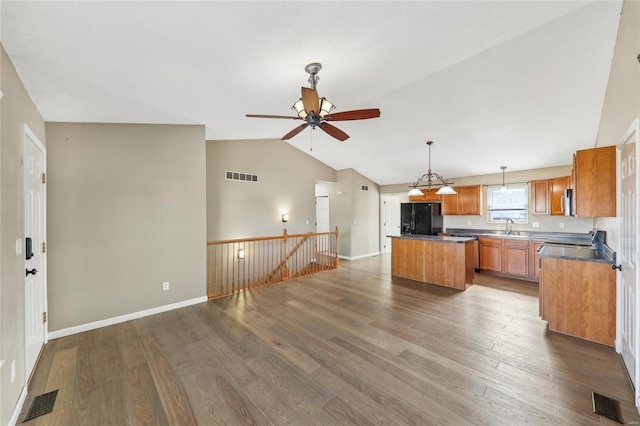 kitchen featuring a kitchen island, visible vents, black fridge with ice dispenser, and wood finished floors