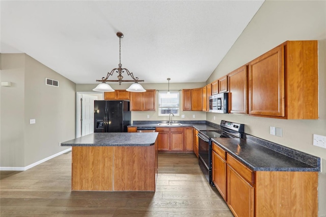 kitchen with visible vents, dark countertops, vaulted ceiling, light wood-type flooring, and black appliances