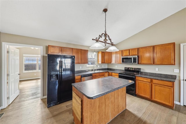 kitchen featuring light wood-type flooring, dark countertops, a center island, and black appliances