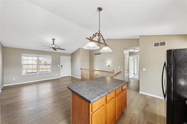 kitchen featuring visible vents, lofted ceiling, dark countertops, dark wood-style flooring, and freestanding refrigerator