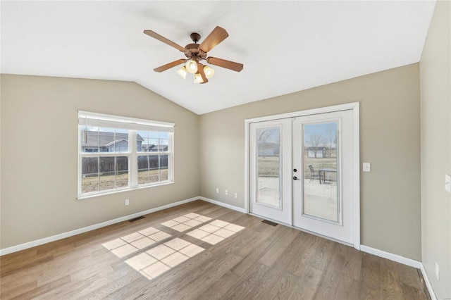 empty room featuring lofted ceiling, french doors, wood finished floors, and visible vents