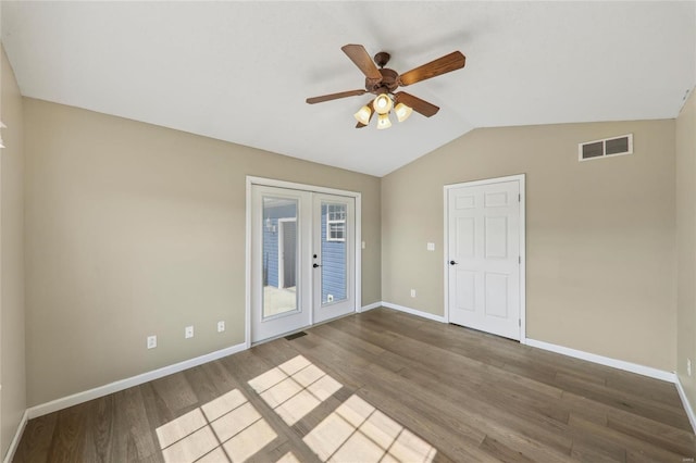 empty room featuring lofted ceiling, wood finished floors, visible vents, baseboards, and french doors