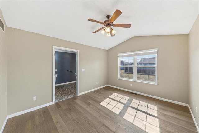 unfurnished room featuring visible vents, vaulted ceiling, baseboards, and wood finished floors