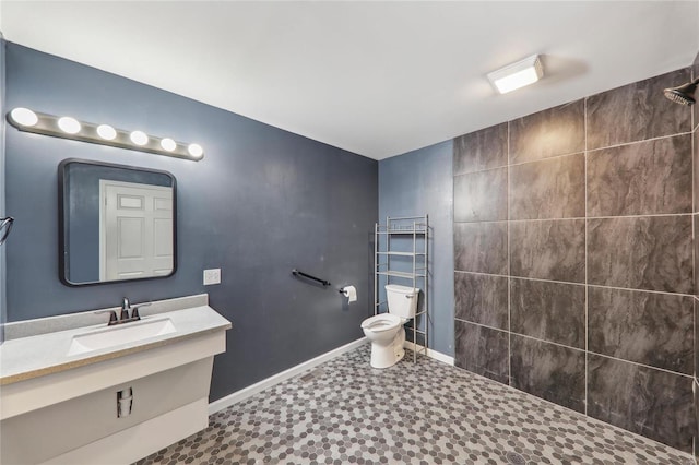 full bath with vanity, a tile shower, toilet, and baseboards