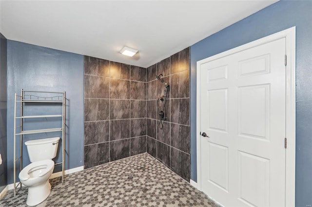 full bath featuring baseboards, a tile shower, and toilet