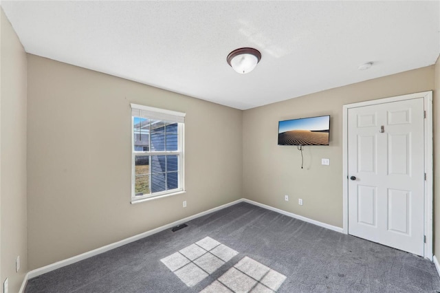 unfurnished room with carpet, visible vents, and baseboards