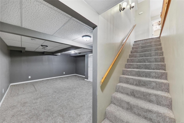 stairs featuring carpet floors, a drop ceiling, and baseboards