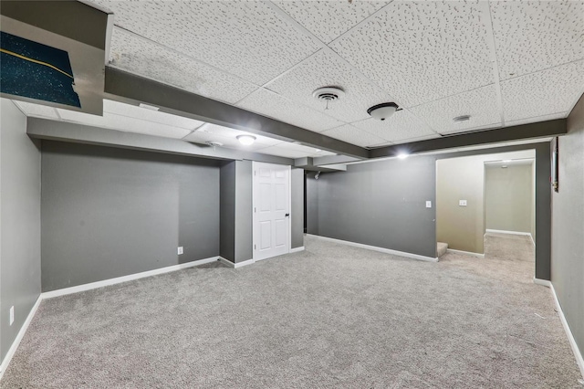 finished basement featuring a paneled ceiling, carpet, visible vents, and baseboards