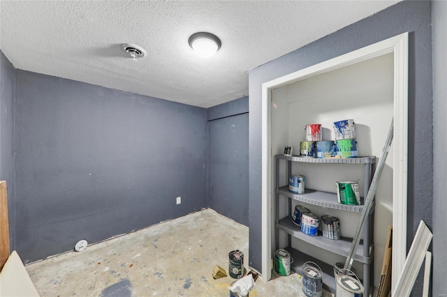 unfurnished room featuring concrete floors, visible vents, and a textured ceiling