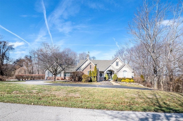 traditional-style house featuring a front lawn and aphalt driveway