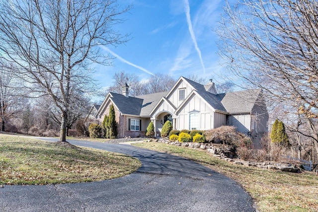 view of front of house with driveway, a chimney, and board and batten siding