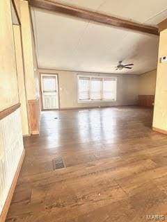 spare room with a ceiling fan, wood finished floors, visible vents, baseboards, and lofted ceiling with beams