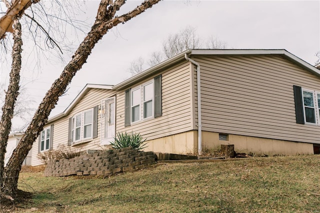 view of side of home with a yard and crawl space