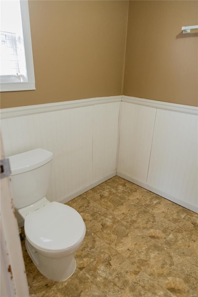 bathroom featuring a wainscoted wall and toilet