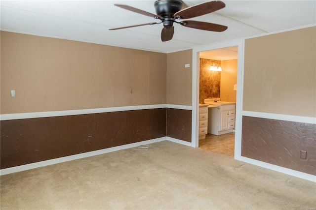 empty room with a sink, baseboards, ceiling fan, and carpet flooring