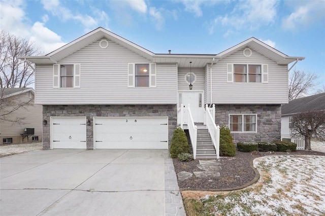 bi-level home featuring a garage, stone siding, and concrete driveway