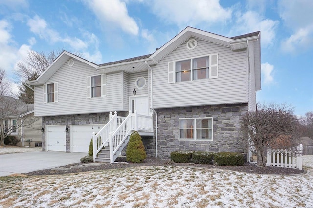 bi-level home featuring driveway, stone siding, and a garage