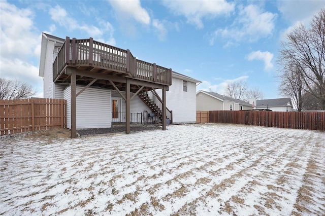 snow covered house with a fenced backyard, stairs, and a deck