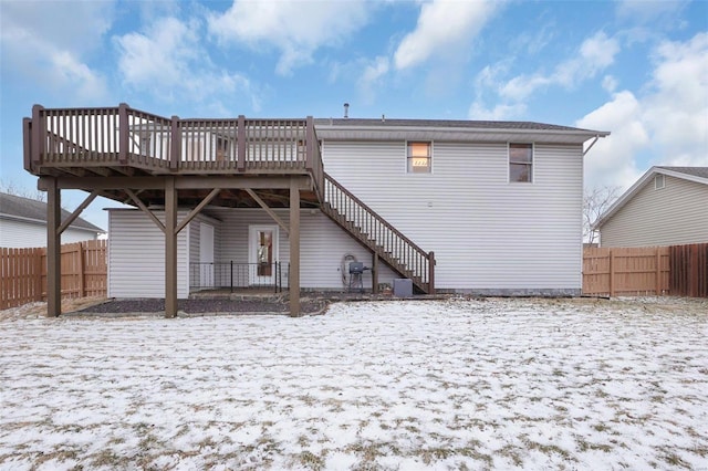 snow covered rear of property featuring stairs, fence, and a wooden deck