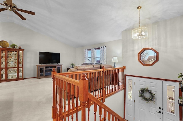 interior space with lofted ceiling, ceiling fan with notable chandelier, and light colored carpet