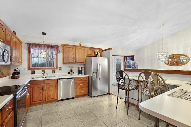 kitchen featuring lofted ceiling, a sink, light countertops, appliances with stainless steel finishes, and decorative light fixtures