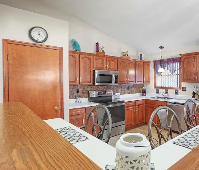 kitchen with lofted ceiling, hanging light fixtures, stainless steel appliances, light countertops, and a sink