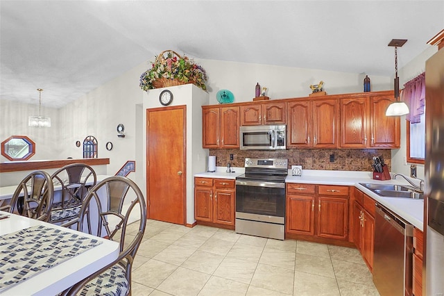 kitchen with stainless steel appliances, pendant lighting, light countertops, and a sink