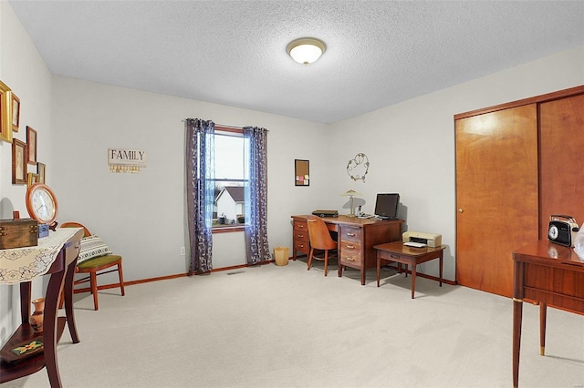 carpeted office with visible vents, a textured ceiling, and baseboards