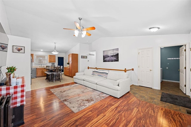 living area featuring visible vents, baseboards, vaulted ceiling, a ceiling fan, and light wood-style floors