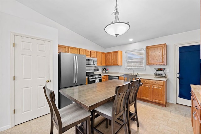 kitchen featuring baseboards, lofted ceiling, stainless steel appliances, light countertops, and a sink