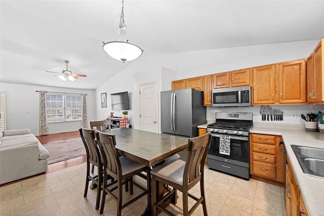 kitchen featuring lofted ceiling, light countertops, appliances with stainless steel finishes, a ceiling fan, and open floor plan